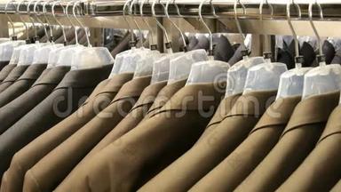棕色和灰色的男士`夹克挂在商场的男士服装店的衣架上。 一大群男人穿`西装